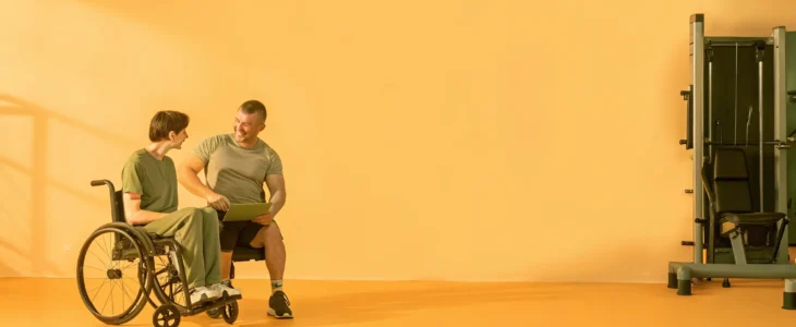 Physical therapist supporting a spinal cord injury patient in a rehabilitation gym