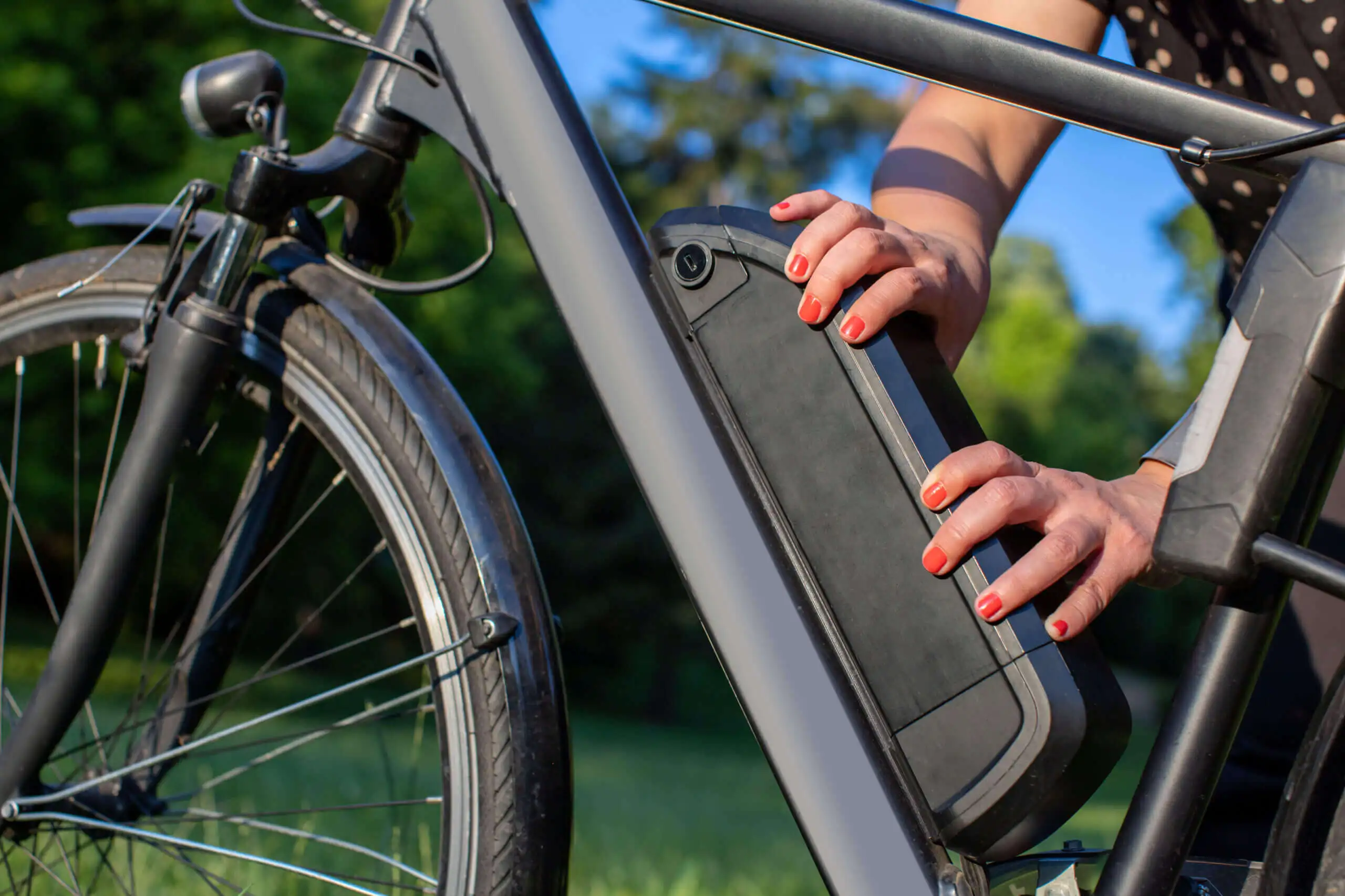 detail of woman holding an electric bike battery mounted on fram