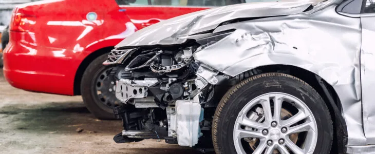 A damaged car with a smashed front end sits in a lot, showing the concern many drivers have about can you drive a crashed car after an accident.