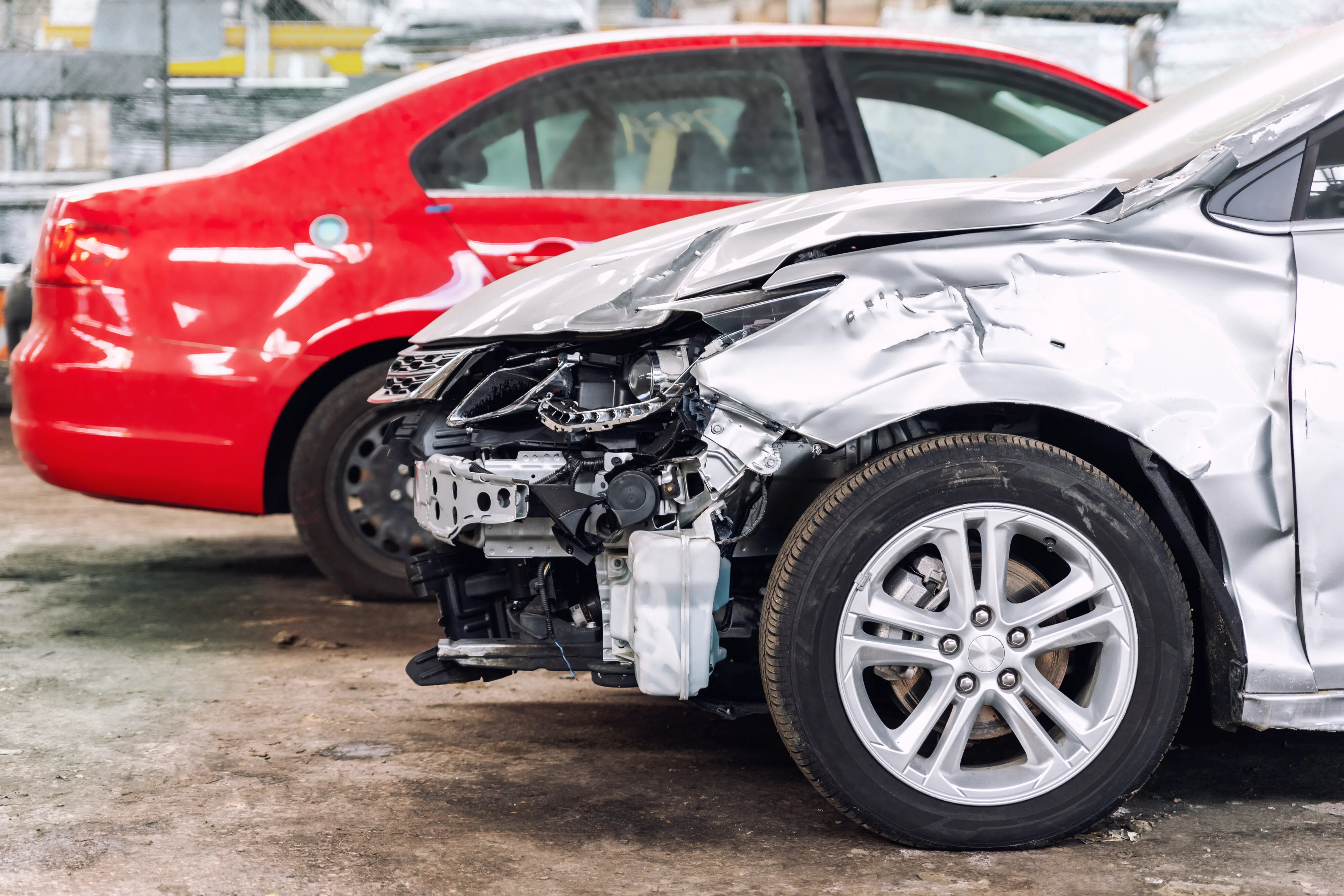 A damaged car with a smashed front end sits in a lot, showing the concern many drivers have about can you drive a crashed car after an accident.