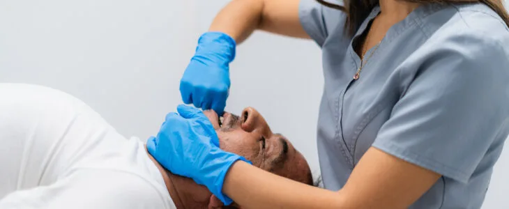 A medical professional examines a patient’s face after a crash, showing the painful and serious effects of car accident face injuries.