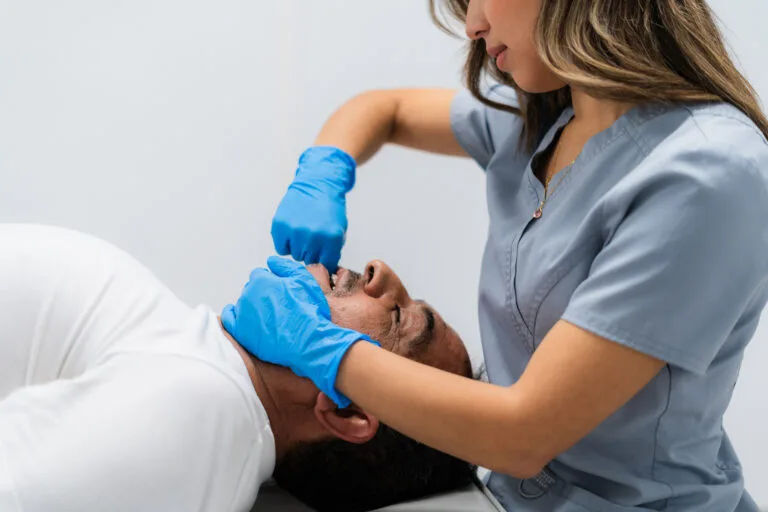 A medical professional examines a patient’s face after a crash, showing the painful and serious effects of car accident face injuries.