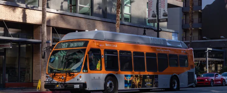 A Los Angeles city metro bus drives down an urban street, representing real scenarios connected to city bus accident settlements in California.