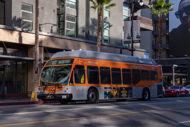 A Los Angeles city metro bus drives down an urban street, representing real scenarios connected to city bus accident settlements in California.