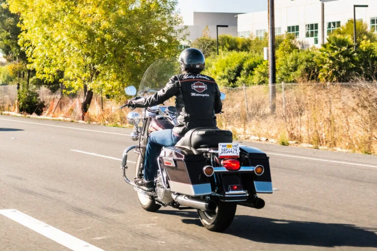 A man rides a motorcycle down a California road on a sunny day, representing the common dangers of riding a motorcycle faced by riders statewide.