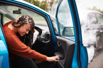 Injured woman holding her neck in pain after a crash and wondering how much does an accident lawyer cost.