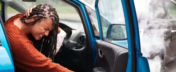 Injured woman holding her neck in pain after a crash and wondering how much does an accident lawyer cost.
