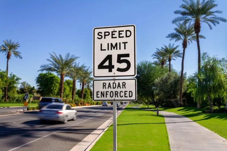 A speed limit sign on a California street that says speeds are radar enforced, representing the laws that define reckless driving in California.