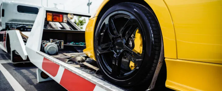 A luxury vehicle is being towed from the road after a collision, illustrating the reality of what happens when you crash a leased car in California.