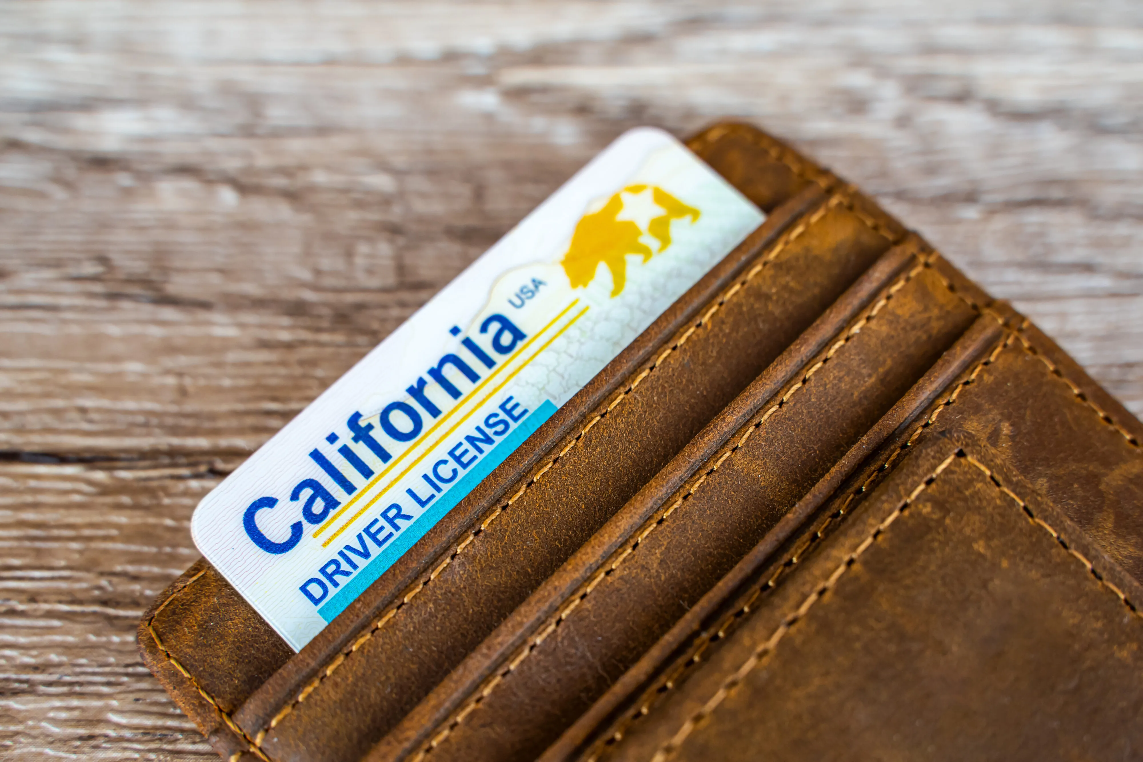 A California driver license tucked inside a wallet, symbolizing the legal questions that arise after a car accident without a license.