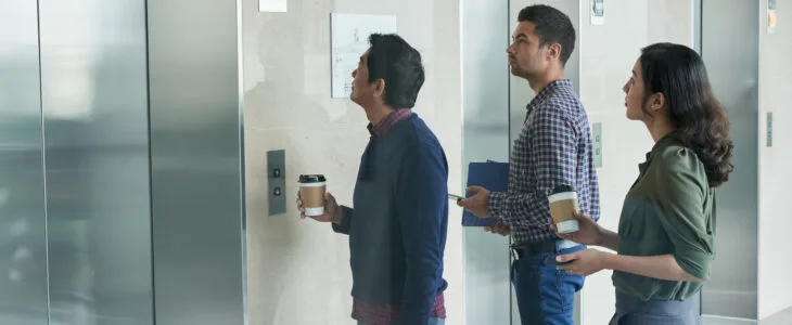 A group of people waits to enter an elevator, representing potential cases that lead to an elevator lawsuit payout.