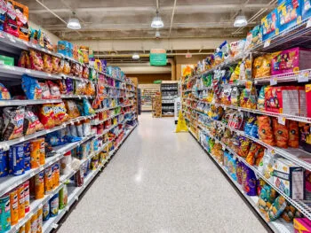 A wet floor sign stands in the middle of a grocery store aisle, representing a common slip and fall in grocery store hazard that can cause injuries.