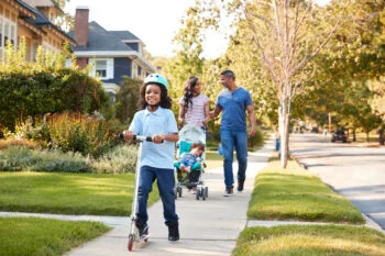 A family walks on a neighborhood sidewalk with a stroller, representing public safety concerns tied to slip and fall on sidewalk cases.