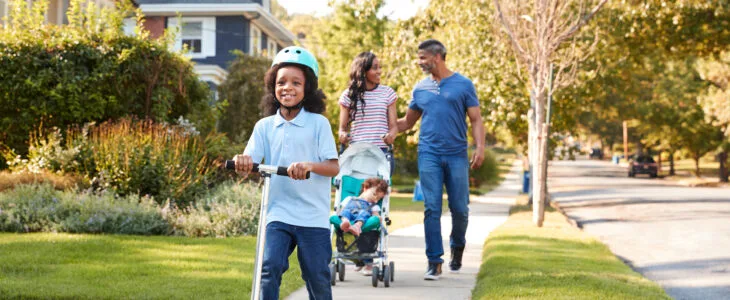 A family walks on a neighborhood sidewalk with a stroller, representing public safety concerns tied to slip and fall on sidewalk cases.