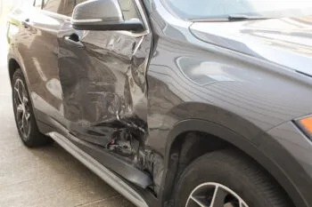 A car with side-impact damage sits on the road, showing the aftermath of a T-bone car accident settlement situation.