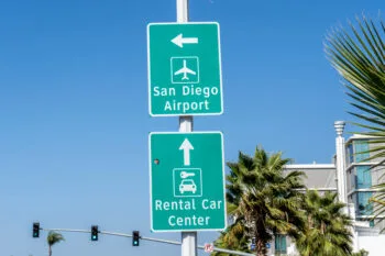An airport rental car return sign at the San Diego Airport, representing situations that raise questions about what happens if you wreck a rental car in California.